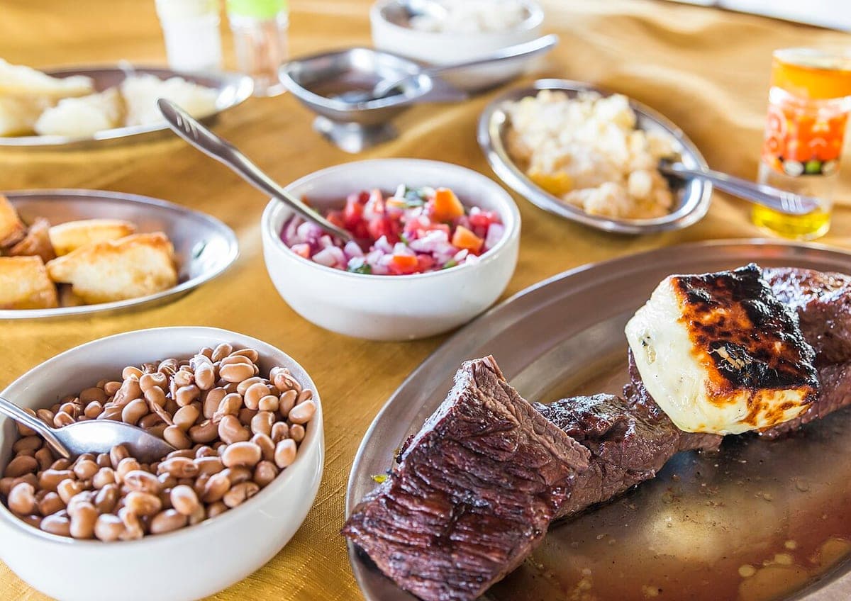 Carne de sol com queijo de coalho assado, feijão e acompanhamentos na mesa